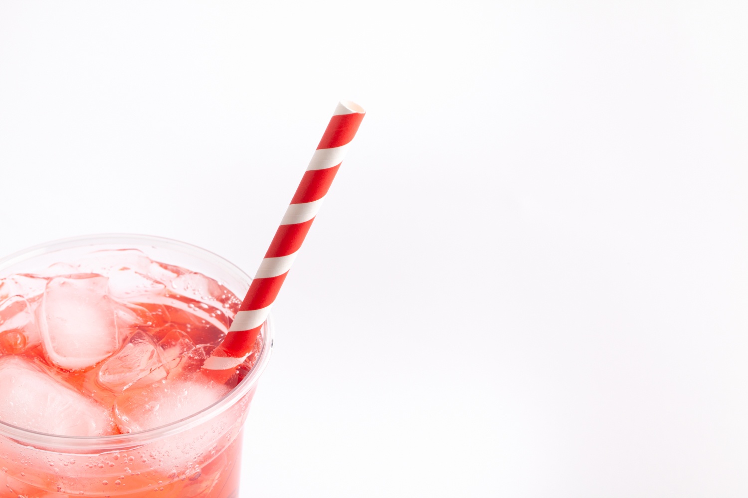 red fizzy drink in clear cup with red rainbow straw