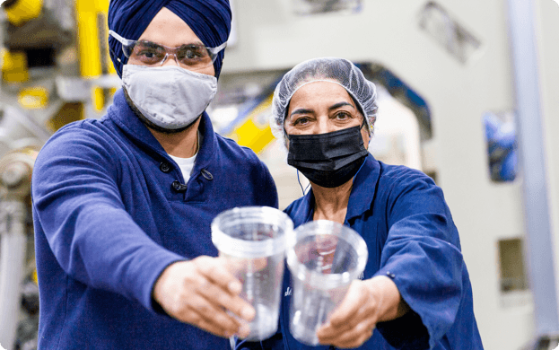 two warehouse workers holding up clear cup products to camera