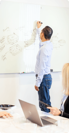 employee drawing on whiteboard, other employees watching