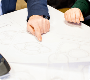 zoomed in on employees hands pointing at section of product sketch