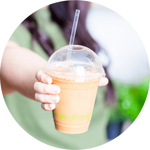 person holding up smoothie in clear cup with lid and straw