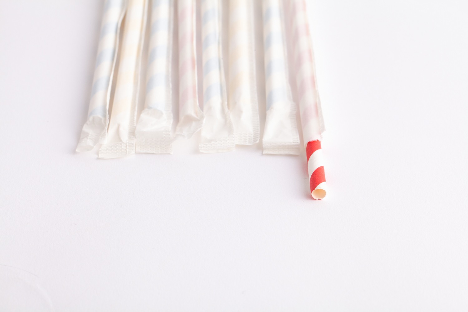 row of wrapped straws with one unwrapped showing candycane pattern on straw