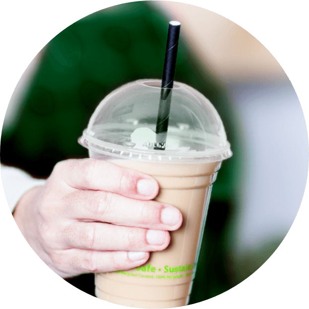 person holding up frappuccino in clear cup with lid and straw